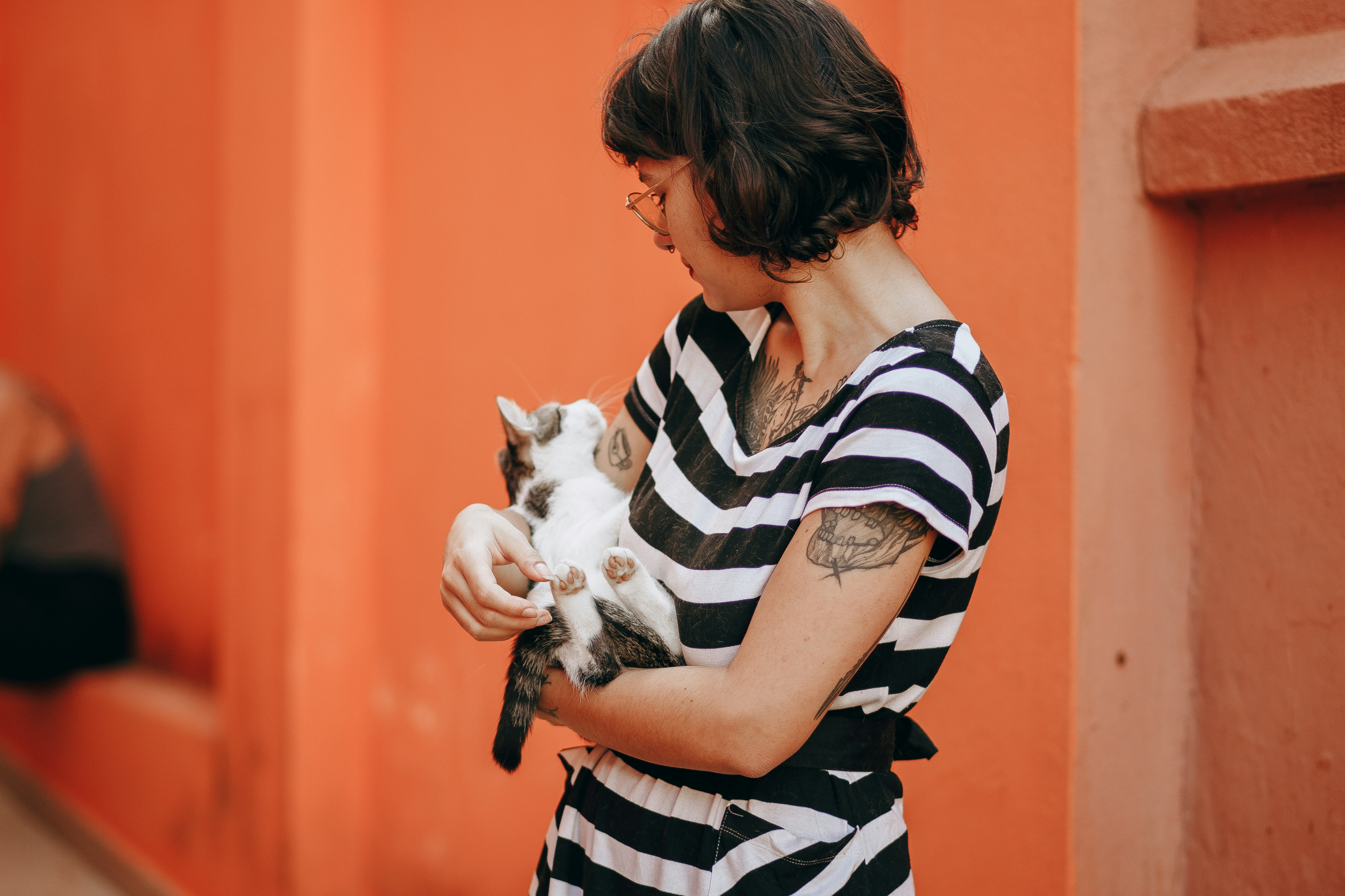 woman in black and white stripe shirt carrying white cat